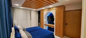 una camera con letto blu e televisore di RABAT RESIDENCE - rooms & aparts a Rabat