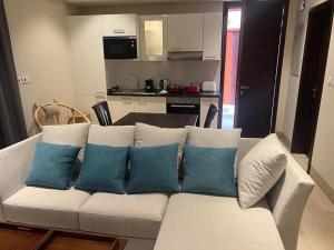 um sofá branco com almofadas azuis numa cozinha em Glory Salalah Miko 2 em Salalah