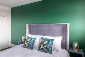 a bedroom with a green wall and a bed with pillows at Centralised Horton Place with FREE PARKING by Prescott Apartments in Bristol