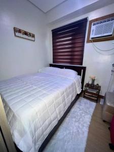 um quarto com uma cama branca e uma janela em JustAnn Escape Staycation em Manilla