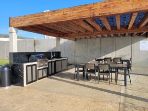 a patio with a grill and tables and chairs at Seafront Luxury Condo in Rosarito with Pool & Jacuzzi in Rosarito