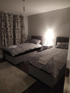 a bedroom with two beds and a lamp and a window at Spacious Two bedroom City apartment Longs Place, Dublin 8 in Dublin