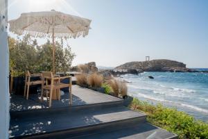 a wooden deck with a table and an umbrella on the beach at Portara Seaside Luxury Suites in Naxos Chora