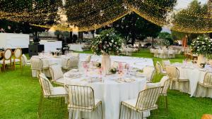 Hacienda El Carmen Hotel & Spa في Portes Gil: إعداد طاولة لحضور حفل زفاف مع طاولات وكراسي بيضاء
