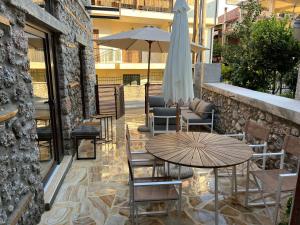 a patio with a table and chairs and an umbrella at Olympus Stone Lodge in Litochoro