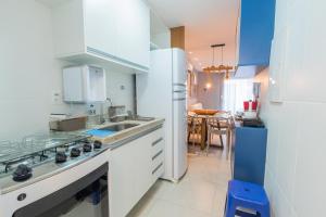 cocina con electrodomésticos blancos y comedor en Apartment in Guarajuba with 2 Comfortable Suites., en Guarajuba