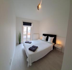 a white bedroom with a large white bed and a window at Huis ALNA 3 in Mechelen