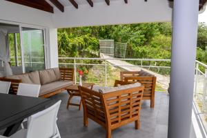 sala de estar con sofá y sillas en el patio en Villa Grenade (haut) - Vue mer et Fort-De-France en Sainte-Luce