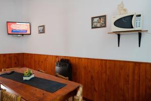 comedor con mesa y TV en la pared en Cabañas Ludmar en Potrero de los Funes