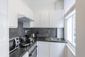eine weiße Küche mit einer Spüle und einer Mikrowelle in der Unterkunft High Street Kensington Apartment in London