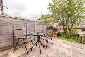 a patio with two chairs and a table and a fence at Contemporary Temple Wall - Contractors, Families, - FREE PARKING by Prescott Apartments in Bristol