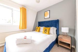 a bedroom with a blue and white bed with yellow pillows at Contemporary Temple Wall - Contractors, Families, - FREE PARKING by Prescott Apartments in Bristol