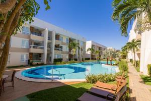 瓜拉久巴的住宿－Apartment in Guarajuba with 2 Comfortable Suites.，棕榈树建筑前的游泳池