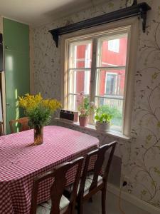 a dining room table with a red table cloth and two windows at Egen stuga och vedeldad bastu in Linghed