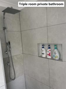 a bathroom with a shower with three milk bottles at Shared house with other guests near shopping center and theme parks in Gold Coast