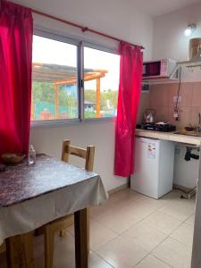 uma cozinha com uma mesa e uma janela com cortinas vermelhas em Cabañas & Apart Yki Shamuaika em Capilla del Monte