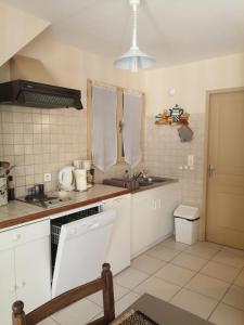 uma cozinha com armários brancos e um lavatório em Le Cigalou em Sainte-Croix-de-Verdon