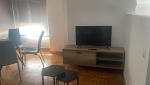 a living room with a television on a dresser with chairs at Valdellera VI in Posada de Llanes