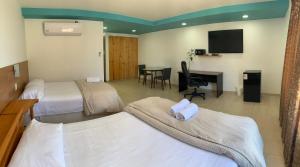 a hotel room with two beds and a desk at Hotel Balistra in Ica