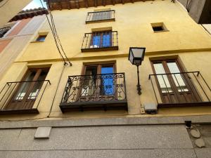 - un bâtiment jaune avec des fenêtres et un balcon dans l'établissement DOMUS ALFILERITOS, à Tolède