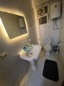 een witte badkamer met een wastafel en een toilet bij شقة مفروشة بالمهندسين محيط نادي الصيد موقع متميز 3غرف نوم مكيفة بالكامل in Caïro