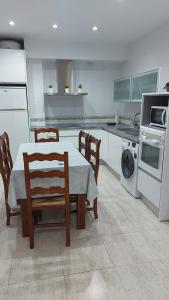a white kitchen with a table and chairs and a stove at Piso luminoso cerca de la playa in Roquetas de Mar
