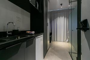 a black and white kitchen with a sink and a shower at Novo e Brilhante Studio em Higienópolis-Academia in São Paulo