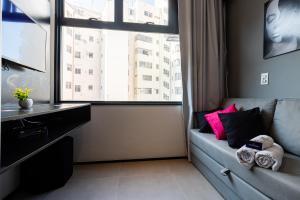 un soggiorno con divano e una grande finestra di Novo e Brilhante Studio em Higienópolis-Academia a San Paolo