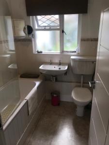 baño con lavabo y aseo y ventana en Ballymacdoe Cottage Cushendall, en Cushendall