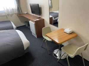 a hotel room with a bed and a desk and a television at Atto Business Hotel Ichinoseki in Ichinoseki