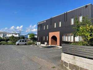 un edificio negro con un coche aparcado en un estacionamiento en Atto Business Hotel Ichinoseki en Ichinoseki