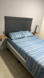 a bed with a blue and white striped comforter at SaVilie 2 - Seguridad y Comfort in Guadalajara