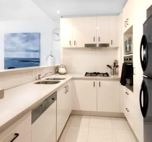 黃金海岸的住宿－Southport Sea Views - Shores Apartment，白色的厨房配有白色橱柜和水槽