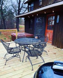 a patio with a table and chairs on a deck at 3 Bedroom log cabin with hot tub at Bear Mountain in Eureka Springs