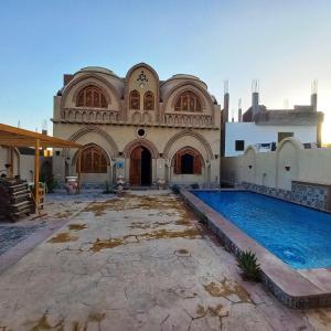 a large building with a swimming pool in front of it at Mystical habou domes villa in Luxor