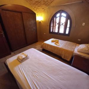 two beds in a room with a window at Mystical habou domes villa in Luxor
