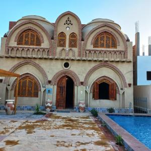 un edificio con piscina frente a él en Mystical habou domes villa, en Luxor