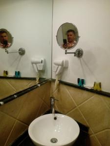 un hombre tomando una foto en un espejo del baño en Salvatore Room With Breakfast- Garden View en Alexandría