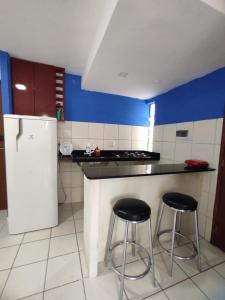 eine Küche mit einem weißen Kühlschrank und 2 Barhockern in der Unterkunft Flat Smart Home in São Luís