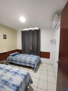 een slaapkamer met 2 bedden en een raam met gordijnen bij Flat Smart Home in São Luís