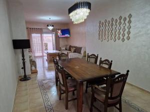 a dining room with a wooden table and chairs at Appartement Saidia avec piscine in Saïdia