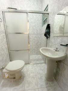 a white bathroom with a toilet and a sink at SUÍTE PRIVATIVA RIVIERA & ITAGUARÉ 100mts de 2 praias! in Bertioga