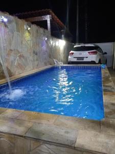 un coche estacionado junto a una piscina con una fuente en Casa inteira ITANHAÉM Piscina AQUECIDA, Churrasqueira e Wi-fi, en São Paulo