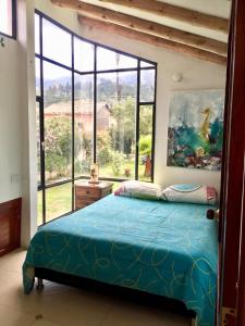 1 dormitorio con cama azul y ventana grande en El Nido de Paso, en Tibasosa
