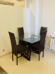 une table en verre avec trois chaises et une table en verre avec dans l'établissement Bhurban Luxury Apartments, à Bhurban