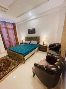 a bedroom with a bed and a couch and chairs at Bhurban Luxury Apartments in Bhurban