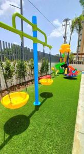 a playground with two swings on the grass at 7F apartamento 3hab piscina ascensor y area social in Santiago de los Caballeros