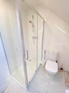 a white bathroom with a shower and a toilet at Agase Way - Stylish 4 Bed Home in Milton Keynes