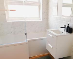 een witte badkamer met een wastafel en een raam bij Apartment by the Royal Ramsgate Harbour - Sleeps 4 in Kent