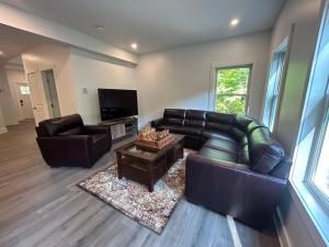 een woonkamer met 2 leren banken en een televisie bij NEW 3 bedroom - Thoroughbred Farm & Lake Views! in Saratoga Springs